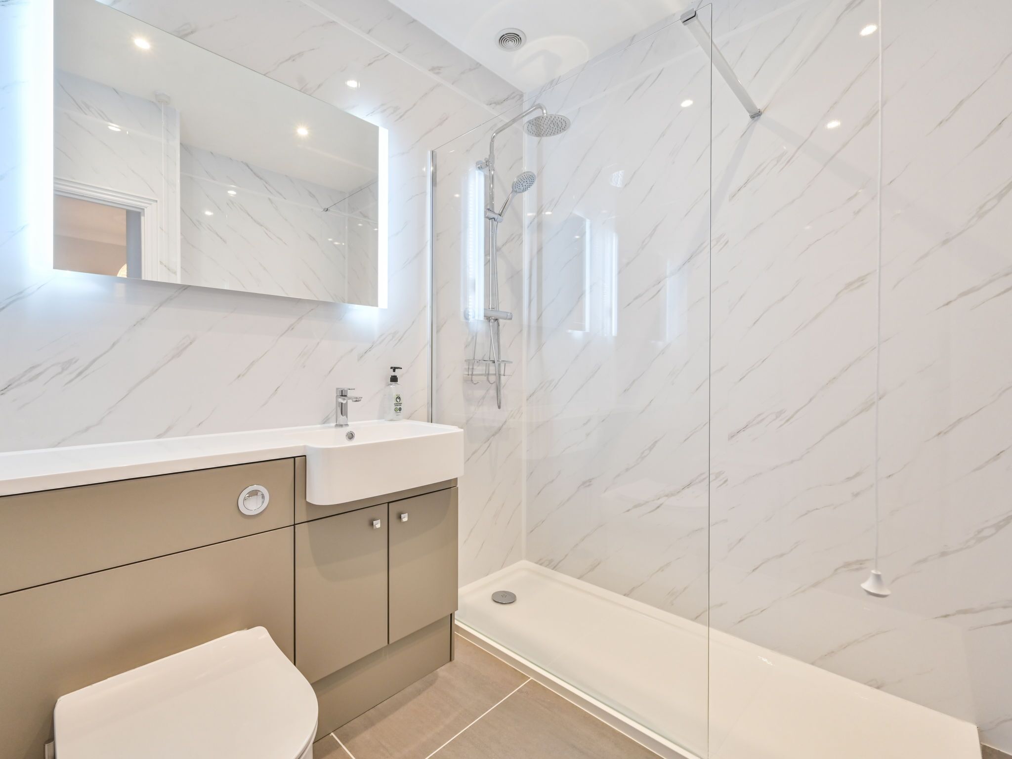 Une salle de bain moderne avec un mur en marbre, un lavabo avec un miroir et un espace douche.