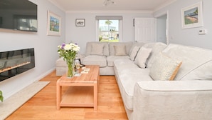 Ein Wohnzimmer mit einem großen Ecksofa, einem Holztisch, einem Flachbildfernseher und einem Kamin.