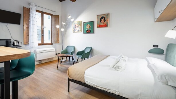 Un dormitorio con cama, escritorio, sillas y televisor.