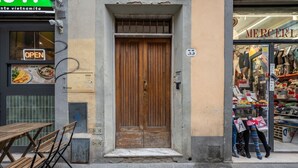 Una puerta de madera con un letrero encima, piso de baldosas y una tienda con maniquíes en el escaparate.