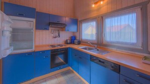 Een kleine keuken met blauwe kastjes, een vaatwasser, een oven en een spoelbak.