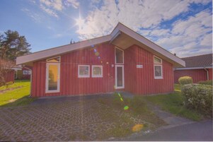 Un edificio rojo con techo inclinado, una puerta principal y dos ventanas.