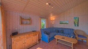 Um quarto aconchegante com paredes de madeira, um sofá azul, um armário de madeira e uma mesa pequena.