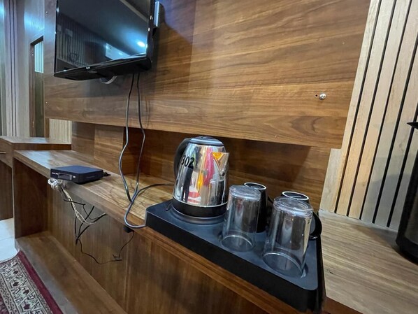 A wooden reception desk with a television mounted above it, a kettle, and a tray with glasses.
