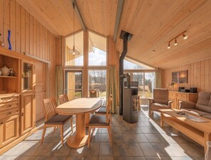 A wooden cabin interior with a dining table, chairs, a sofa, and a fireplace. - Ferienhaus mit Sauna im Ferienpark Mirow (Mirow)