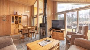 A cozy wooden interior with a fireplace, a TV, and comfortable seating. - Ferienhaus mit Sauna im Ferienpark Mirow (Mirow)