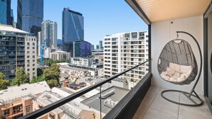 Un balcón con una hamaca colgante, vistas del horizonte urbano y edificios modernos.