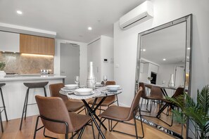 Un comedor moderno con una mesa redonda dispuesta para cuatro personas, rodeada de sillas marrones.