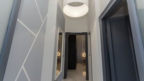 A hallway with a modern light fixture, a dark door, and a tiled floor. - VivimiHome-Navigli Exclusive Apartment (Milan)