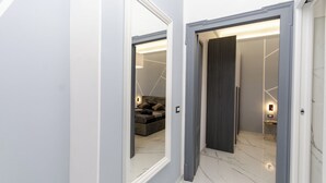 A hallway with a marble floor leading to a room with a sofa and a lamp. - VivimiHome-Navigli Exclusive Apartment (Milan)
