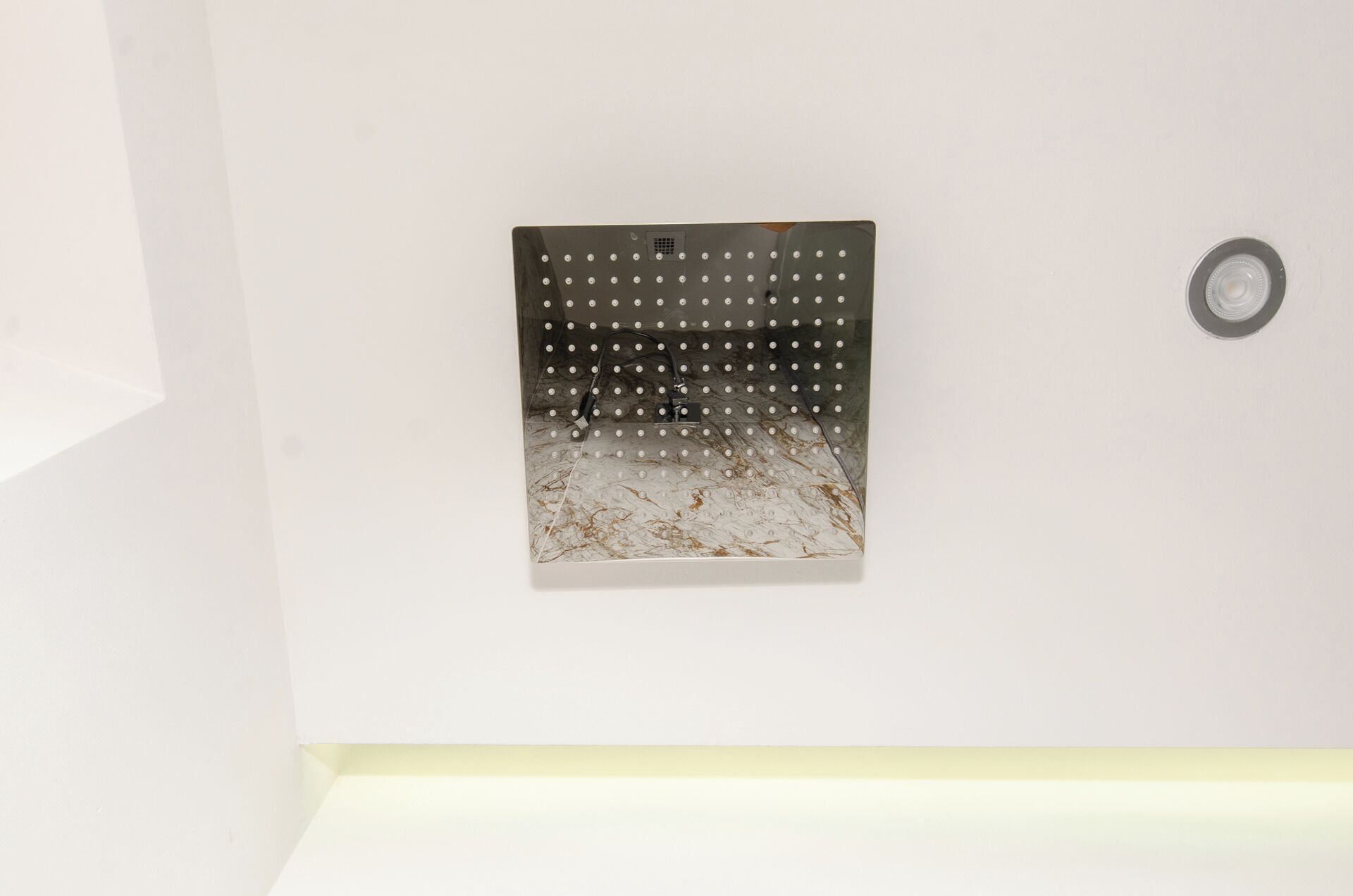 A wall-mounted, perforated metal panel with a grid of holes, likely a vent or decorative element.