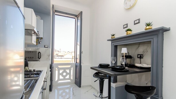 A modern kitchen with a stove, sink, and a dining area with a table and chairs. - VivimiHome-Navigli Exclusive Apartment (Milan)