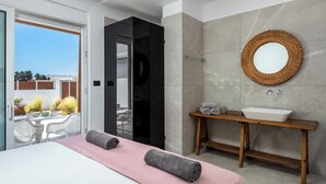 Une chambre à coucher moderne avec un lit, une coiffeuse en bois dotée d’un lavabo et un grand miroir.