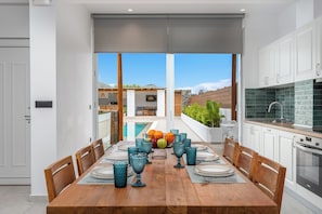 A dining area with a wooden table, chairs, and blue glassware. - Johannes Luxury Villas (Rhodes)