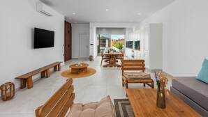 Un salon moderne doté d’un téléviseur, de meubles en bois, d’un coin repas et offrant une vue sur l’extérieur.