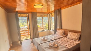 Camera da letto con due letti, pavimento in legno e soffitto spiovente.