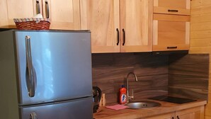 Una cucina con mobili in legno, un frigorifero in acciaio inossidabile, un lavello e un piano di lavoro in legno.