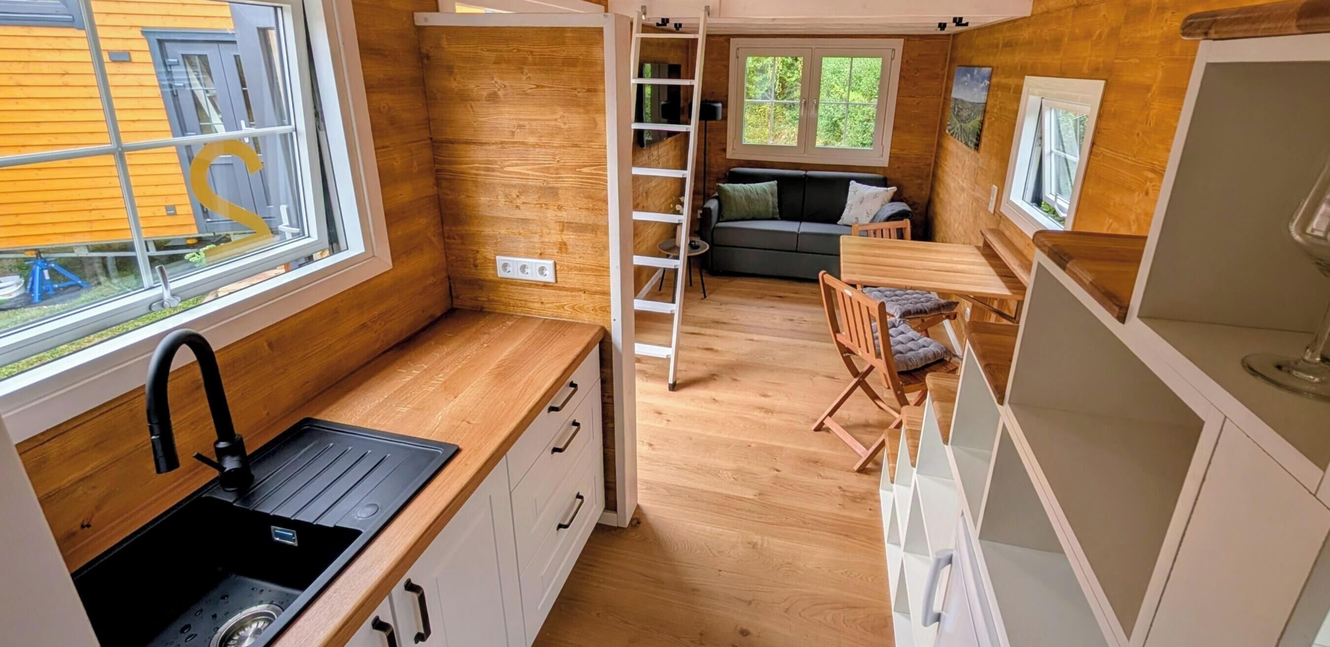 A compact kitchen with a sink, cabinets, and a window overlooking greenery.