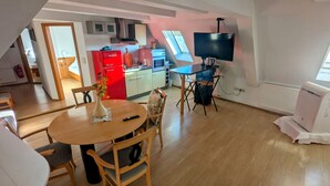 Un espacio habitable compacto con comedor, kitchenette y televisor.