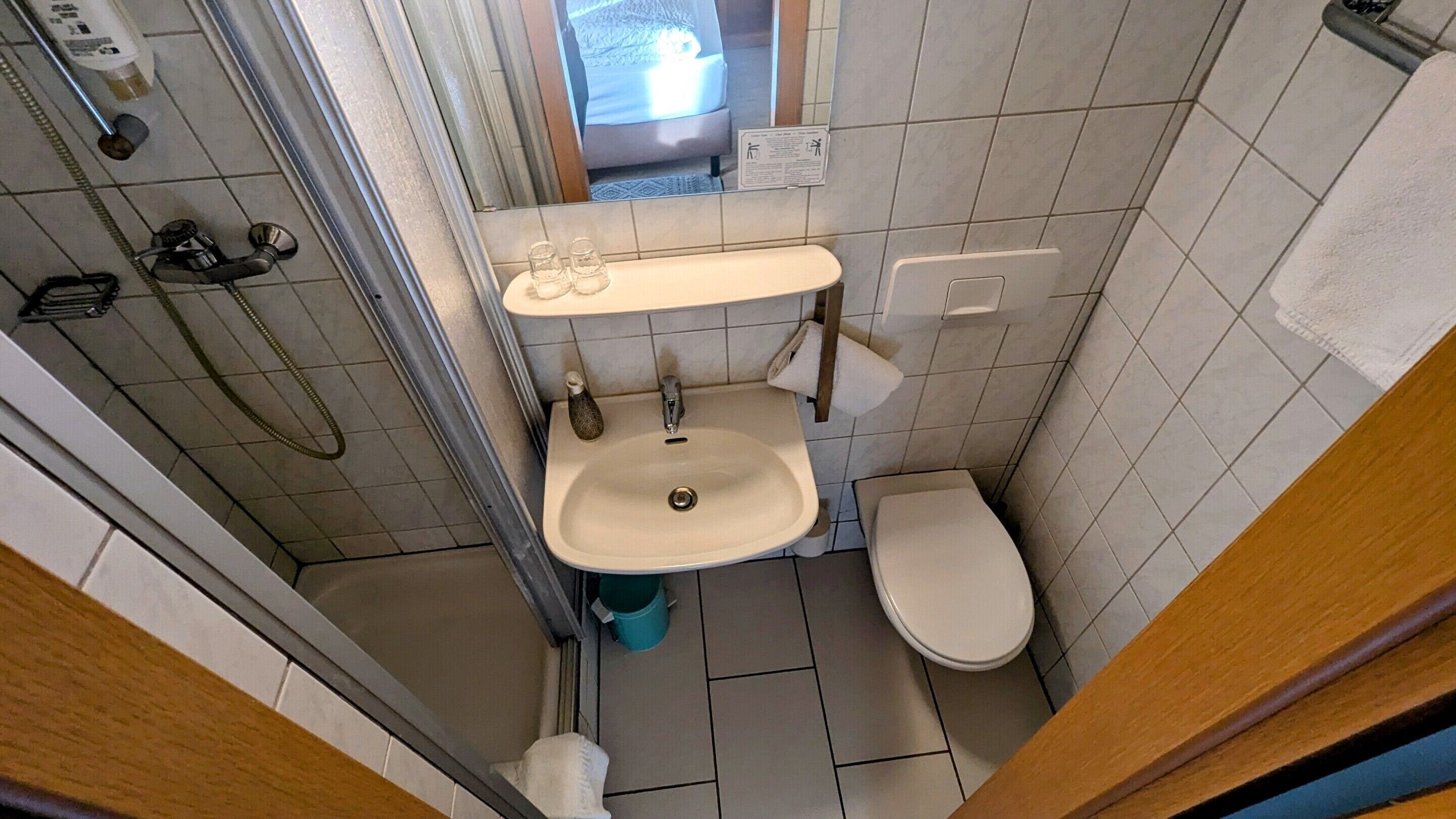 A small bathroom with a toilet, sink, and shower.