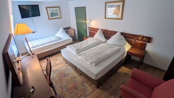 A hotel room with two beds, a desk, a chair, a TV, and a door.