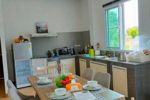A compact kitchen with a dining area, a refrigerator, a microwave, and a window with a view.