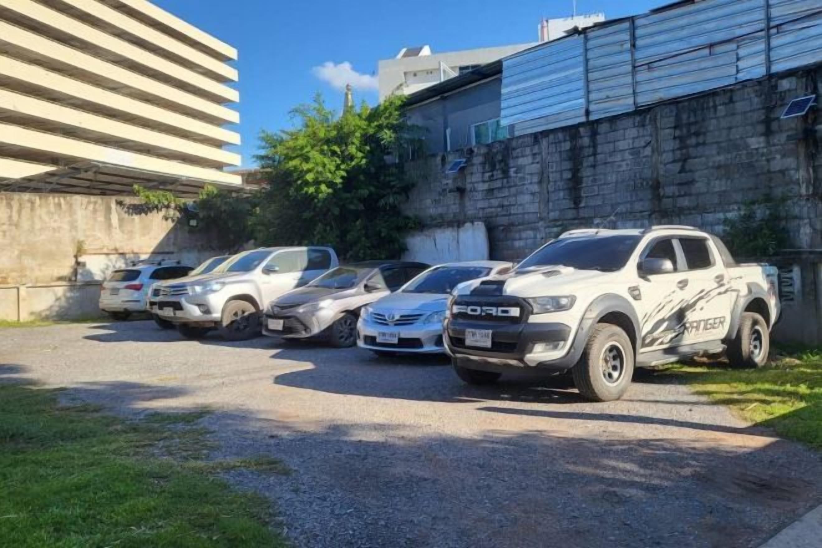 Un espace de stationnement où sont garés plusieurs pick-up blancs.