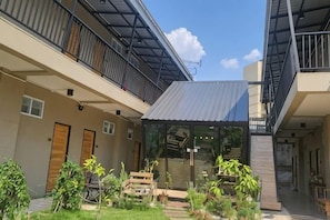 A courtyard with a glass enclosure, wooden furniture, and potted plants. - Hug Udon (Udon Thani)