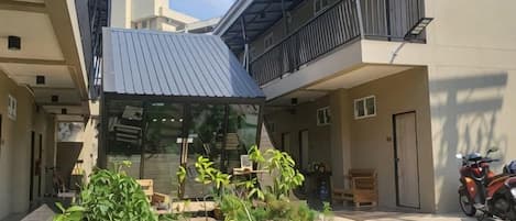 Un patio con una zona de estar techada, una motocicleta y un pequeño jardín.