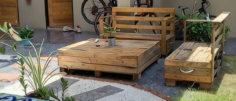 Un patio con un banco de madera, una mesita y macetas con plantas.