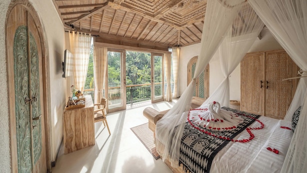 Une chambre à coucher avec un lit à baldaquin, un bureau en bois et une vue sur l’extérieur.