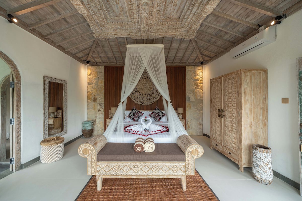Un dormitorio con una cama con dosel, un armario de madera y una pared de piedra.