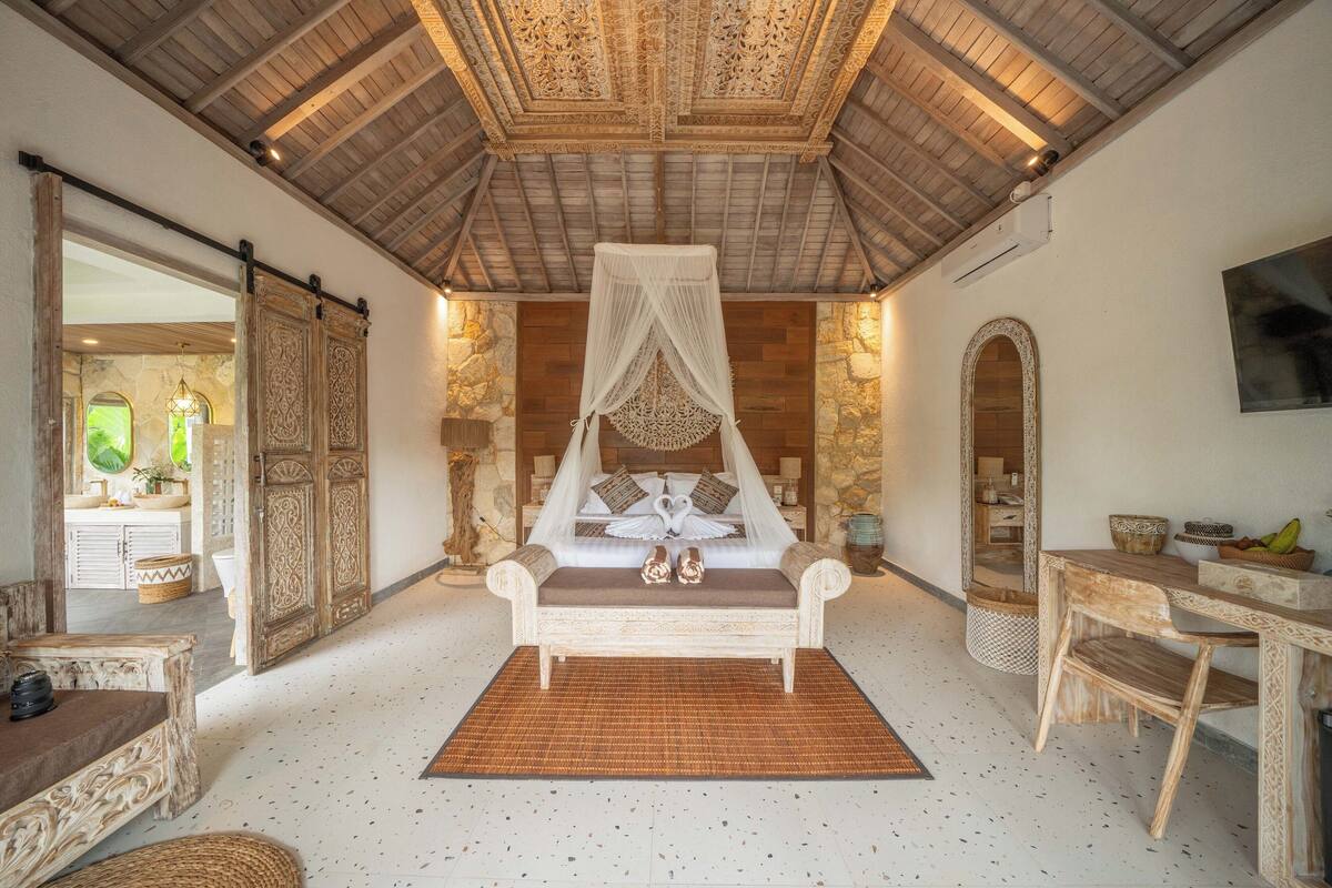 Un dormitorio con cama con dosel, paredes de piedra y un espejo grande.