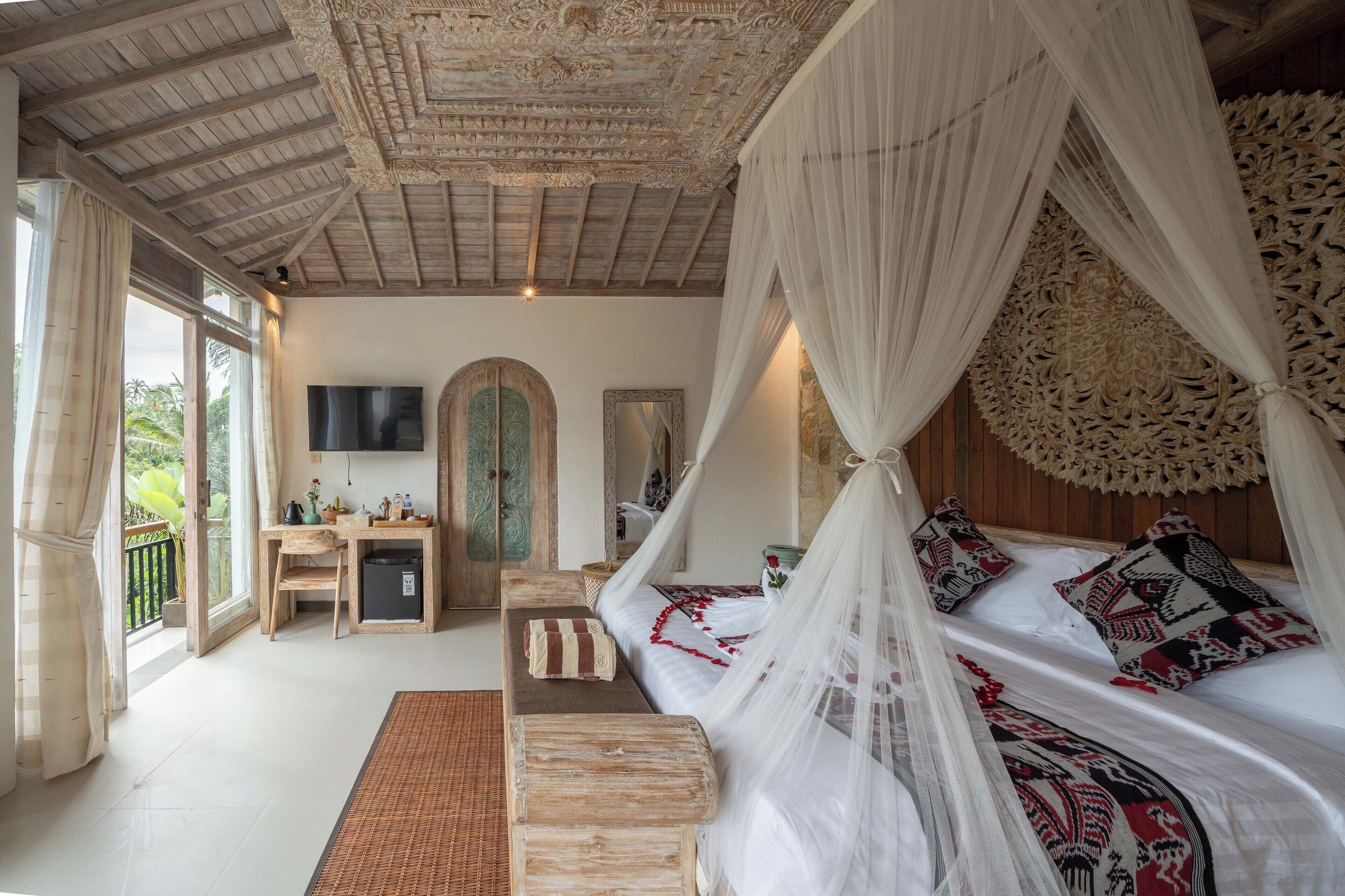 A bedroom with a canopy bed, a desk, and a television.