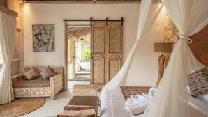 Une pièce comprenant un lit, un canapé, un mur décoratif et une porte-fenêtre donnant sur l’extérieur.