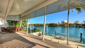 A covered outdoor area with a view of a body of water, seating arrangements, and a glass railing. - Surfers Paradise Escape (Heated Pool) (Surfers Paradise)
