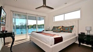 A bedroom with a large bed, a ceiling fan, a TV, and a view of a swimming pool. - Surfers Paradise Escape (Heated Pool) (Surfers Paradise)