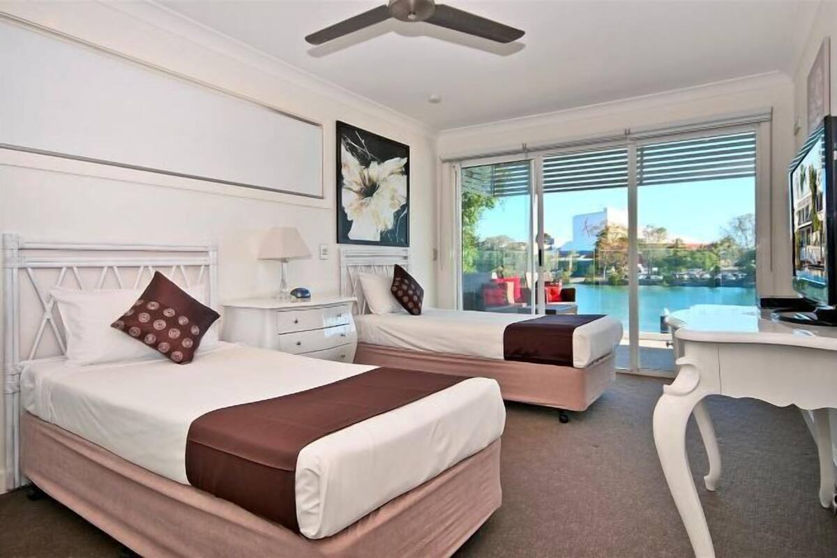 A hotel room with two beds, a desk, and a view of a body of water.