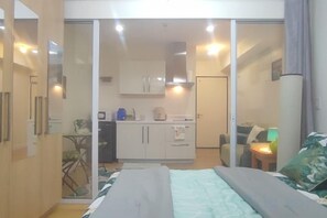 Ein Schlafzimmer mit einem Bett, einer kleinen Küchenzeile und einer Schiebetür zum Badezimmer.