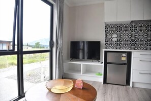A modern kitchen with a TV, a refrigerator, and a dining area with a table and chairs.