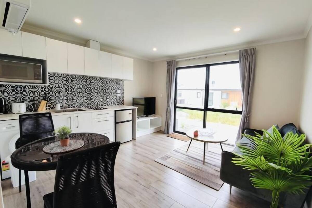 A modern kitchen with white cabinets, a black and white backsplash, and a dining area with a round table and chairs.