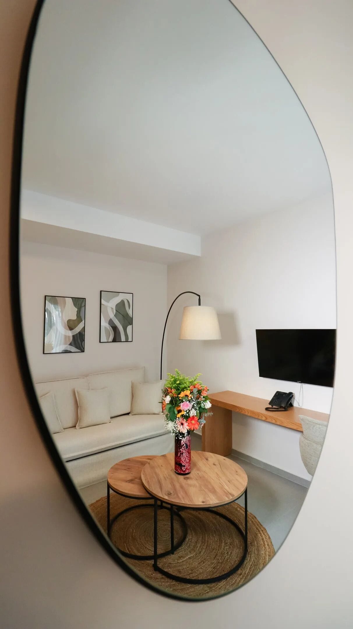 Een moderne woonkamer met een bank, een ronde houten tafel, een bloevas en een lamp.