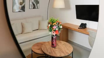Een moderne woonkamer met een bank, een ronde houten tafel, een bloevas en een lamp.