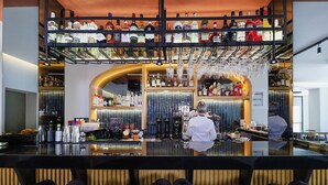 Eine Bar mit Regalen voller Spirituosenflaschen, einem Barkeeper und einer Theke.