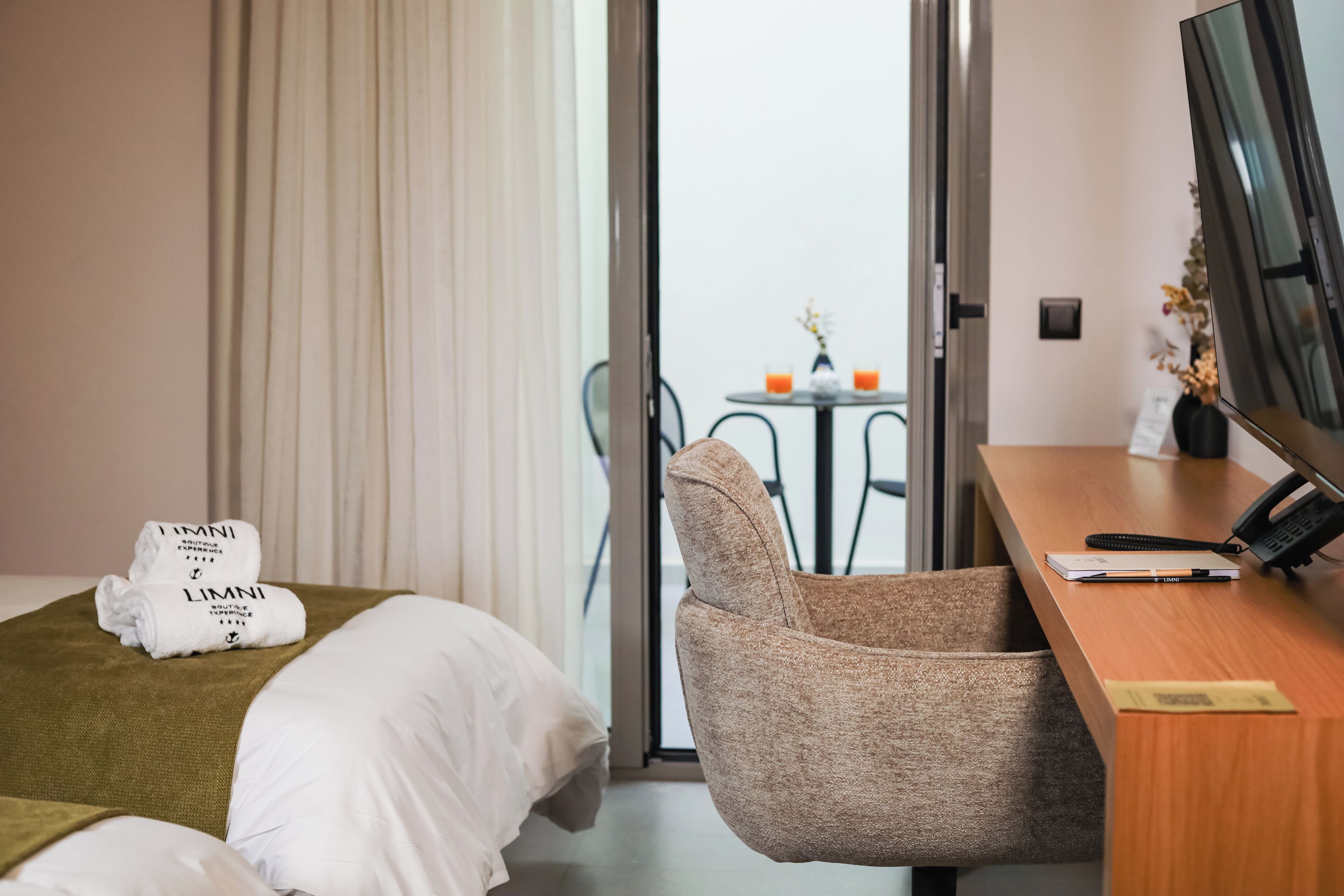 Habitación de hotel con cama, escritorio, silla, televisión y vistas al exterior.