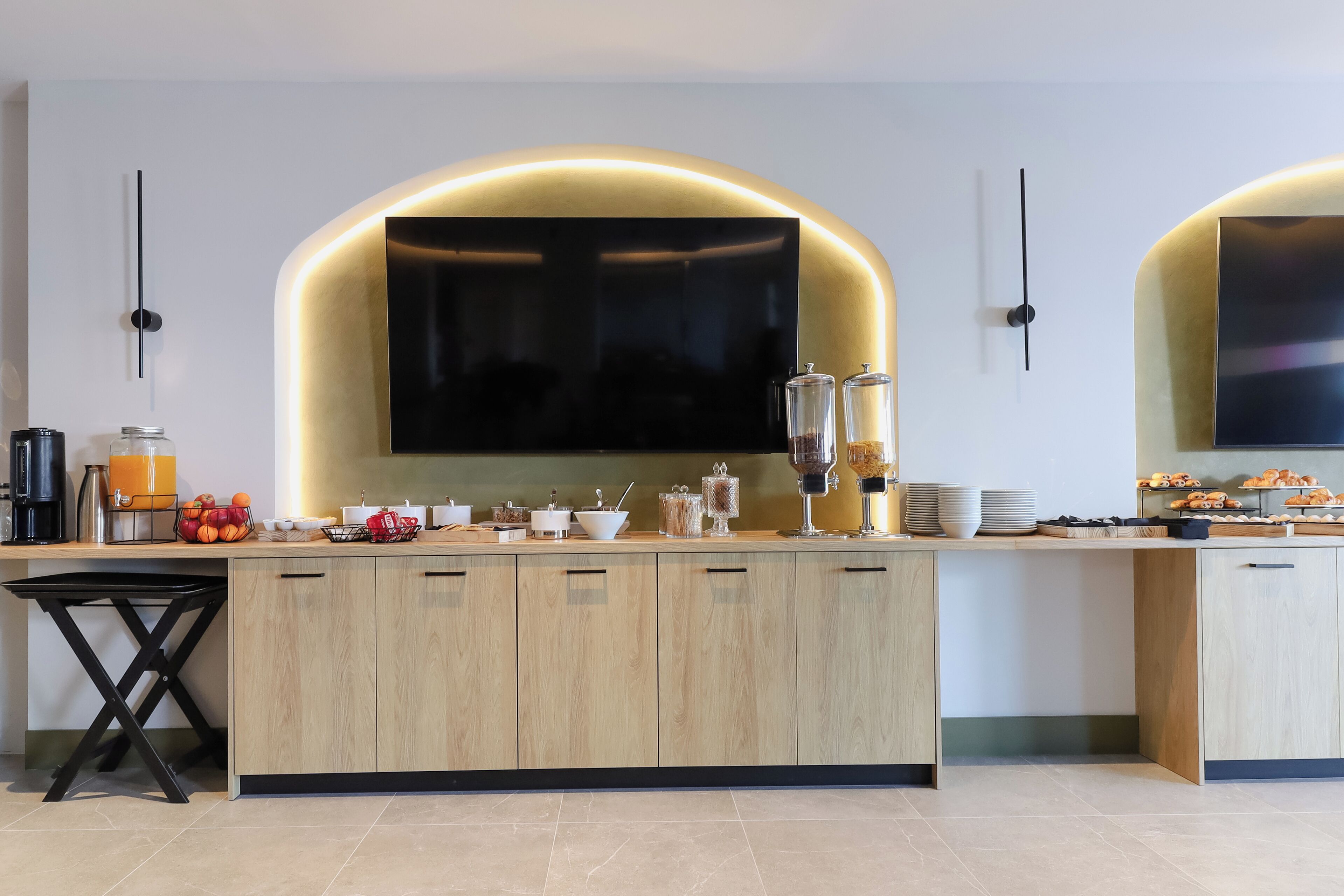 A modern kitchen with a central island, built-in appliances, and a large flat-screen TV.