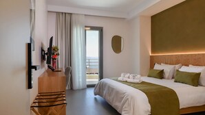 Ein Hotelzimmer mit Bett, Schreibtisch, Stuhl, Fernseher und Meerblick.