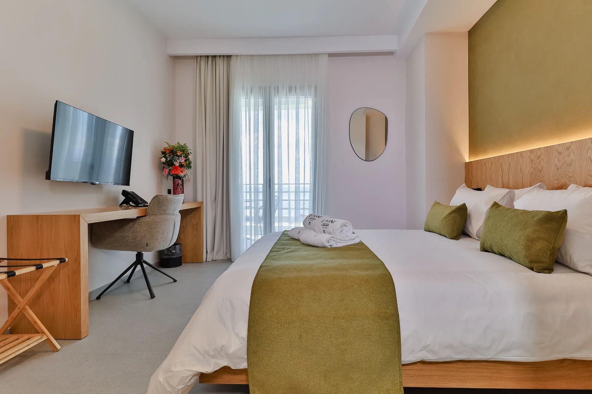 Een hotelkamer met een bed, een bureau, een televisie en een raam met gordijnen.