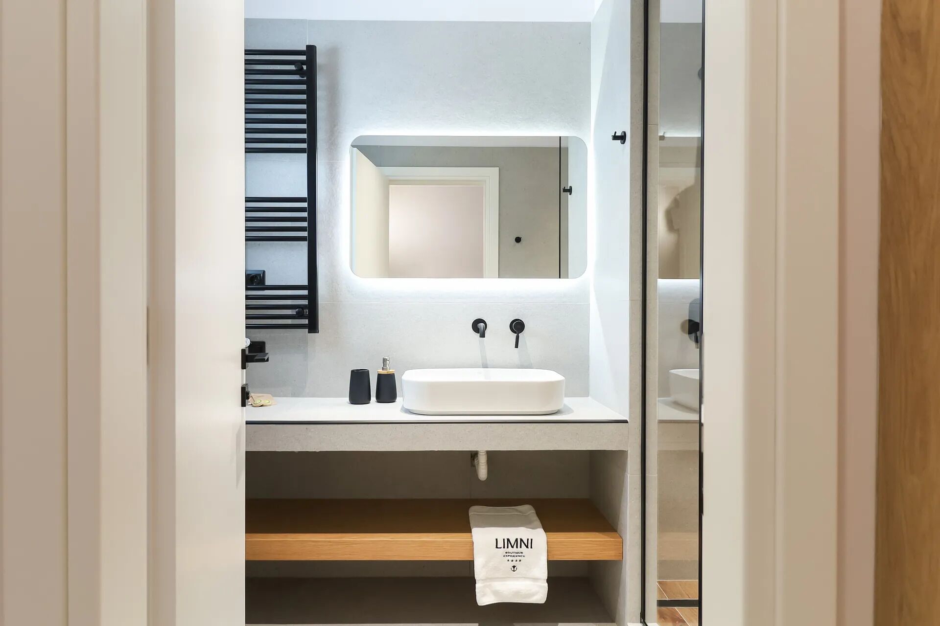 A modern bathroom with a white sink, a mirror above it, and a towel hanging on a rack.