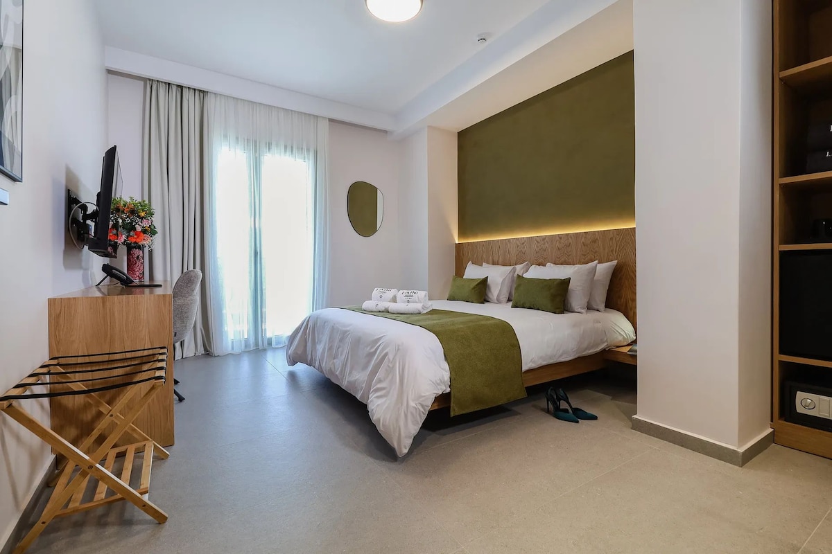 A hotel room with a bed, a desk, a chair, a TV, and a wardrobe.